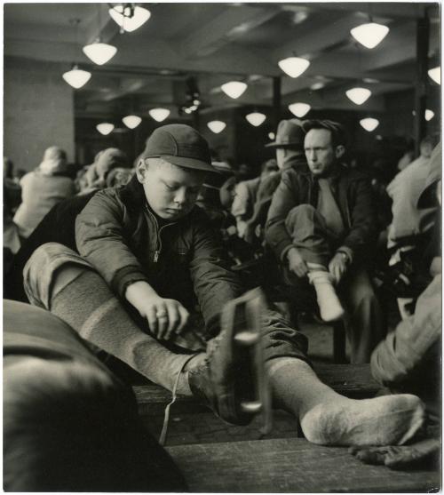 New York City boy putting on ice skates surrounded by people