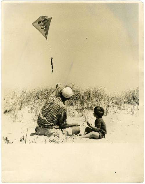 Father flying a kite with son on the beach