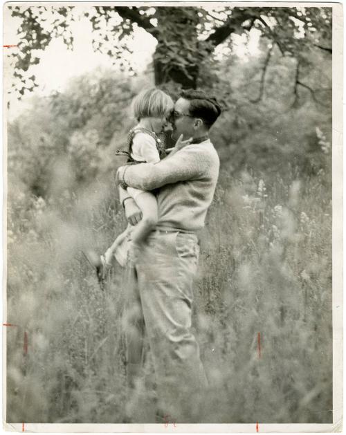 Portrait of father hugging young daughter in grassy field