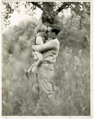 Portrait of father hugging young daughter in grassy field