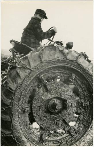 Farm boy driving muddy tractor