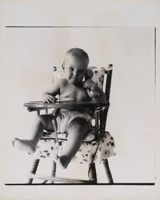 [Portrait of baby in high chair with toy telephone]