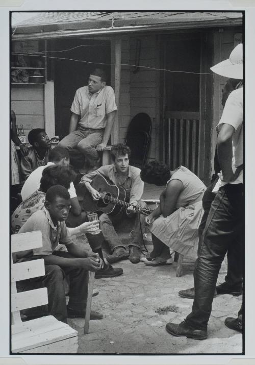 Greenwood, Mississippi, additional photograph from the series Memories of the Southern Civil Rights Movement 
Bob Dylan plays for SNCC workers Bernice Reagon and Mendy Samstein and James Blue outside the SNCC office.