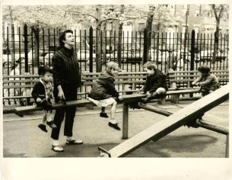 [Four children playing on see-saw with teacher]