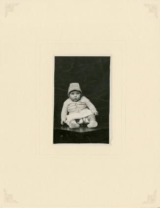 Baby seated on table, held by metal holder