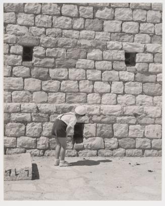 Boy peeping into a hole in the wall, Italy