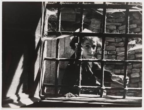 Girl gripping on window bars, Italy