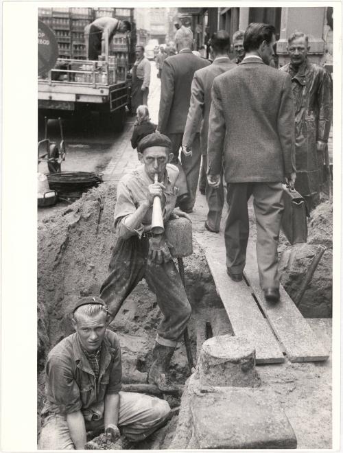 Worker blows horn, as telephone lines are fixed underground, Amsterdam, Holland