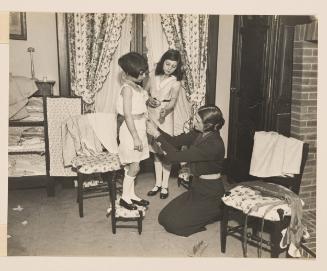 Two girls being fitted for a dress