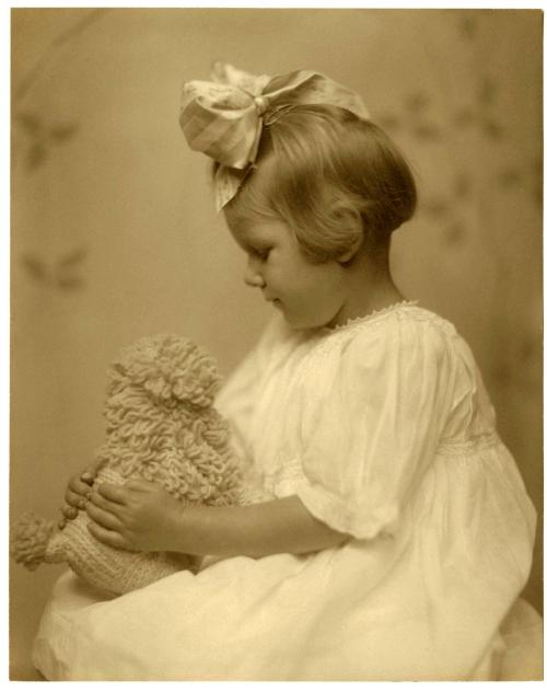 Portrait of seated child, holding knitted stuffed animal