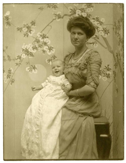 Portrait of mother, seated holding smiling baby