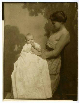 Portrait of mother in profile, seated holding baby facing camera