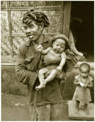 Man with a cigarette in mouth holding an infant, Bali, Indonesia