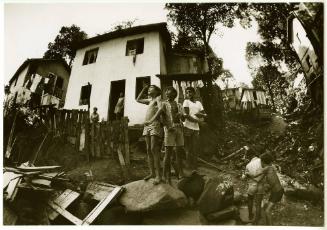 Three boys standing on a rock in the favela, Brazil