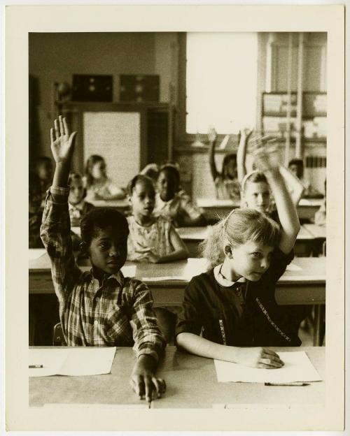 Children in classroom raising their hands