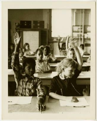 Children in classroom raising their hands