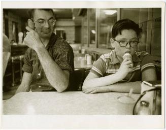 Boy with glasses eating ice cream with father, from the series Big Brother