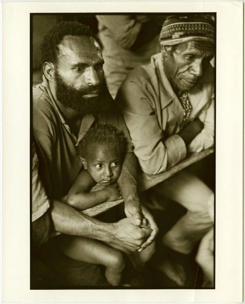 Bearded man with child in his lap, Papua New Guinea