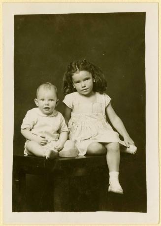 Glen and Linda Dugger [Sister with crossed legs and baby brother seated on table]