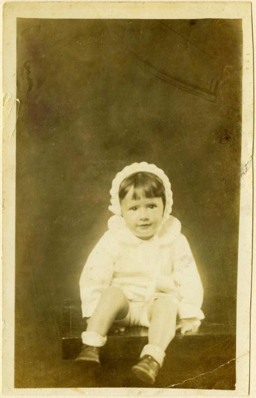 Girl in bonnet seated on table