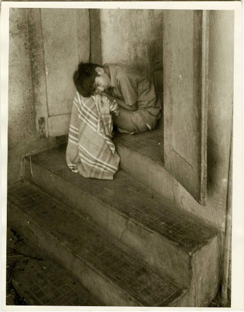 Seated boy in doorway with blanket