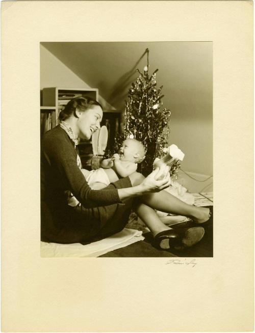 Mother holding a baby next to Christmas tree