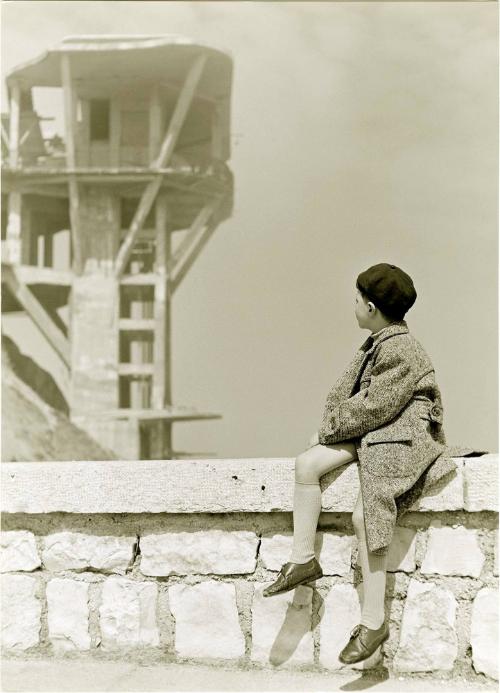 Boy seated on stone ledge looking backwards, Italy