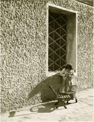 Girl buttoning up jacket against wall, Italy