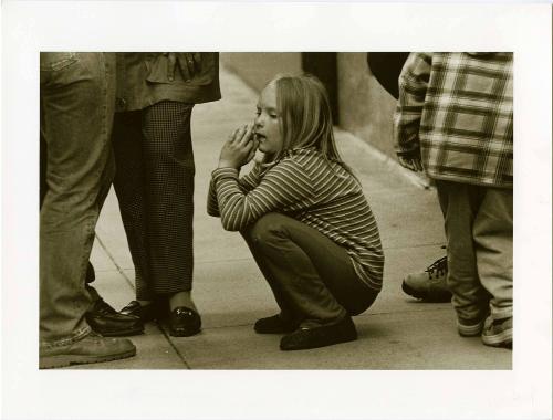 Times Square [Child crouching on ground, legs of adults around her]