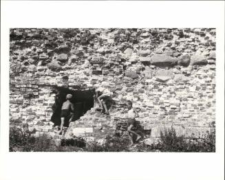 Three boys at play on a ruined wall