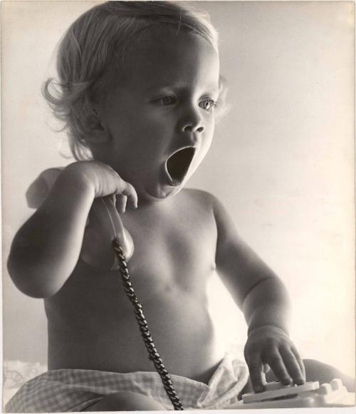 Portrait of yawning baby holding telephone