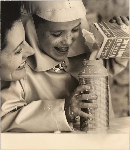 Portrait of mother and child in raincoat pouring milk into thermos