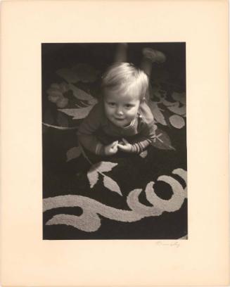 Portrait of toddler boy lying on a rug