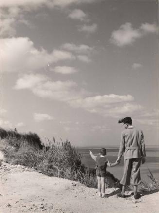 Older boy and younger boy overlooking the ocean with hands held, Italy