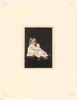 Girl hugging infant seated on table