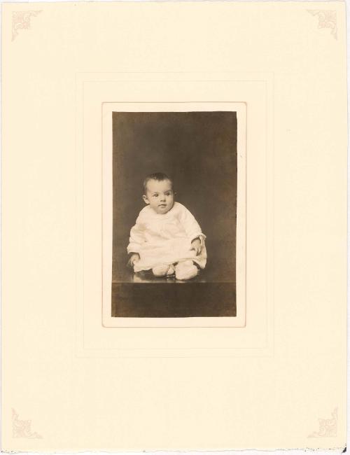 Bemused infant seated on table