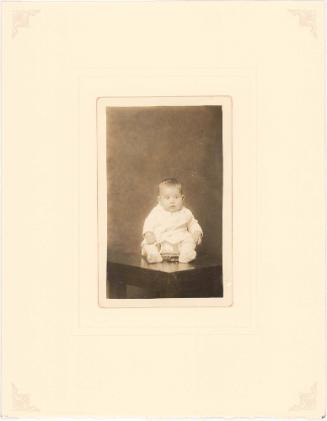 Infant seated in wire brace on table