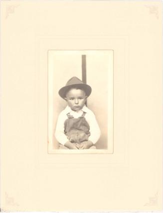 Boy in overalls and hat, striped background