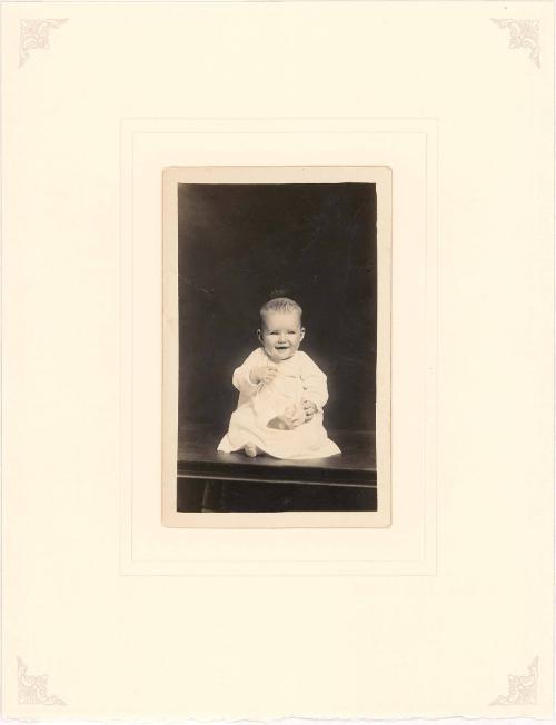 Laughing infant seated on table