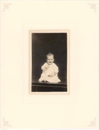 Laughing infant seated on table