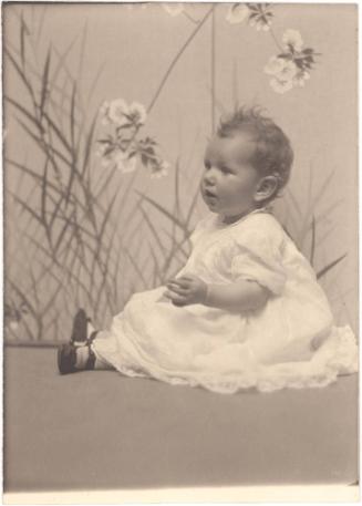 Portrait of seated baby girl with black shoes