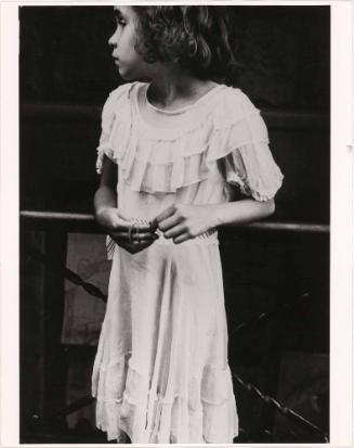 Girl in white dress holding beaded necklace