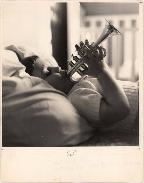 Portrait of boy lying down playing trumpet