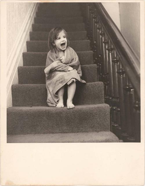 Portrait of young girl wrapped in towel sitting on stairs