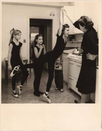 Mother in kitchen with daughters dressed in dance outfits