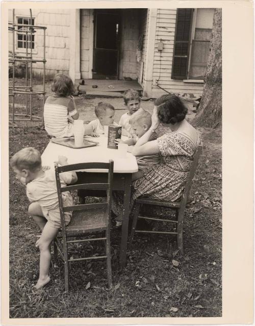 Mother sitting at table in backyard with children