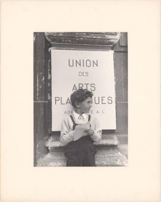 Boy standing in front of Union des Arts Plastiques, Paris