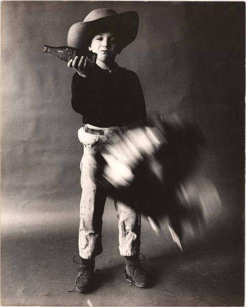 Advertising photograph of boy dressed as cowboy drinking a Coca-Cola