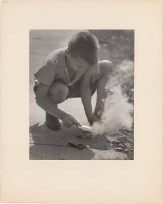 Boy lighting firecrackers on sidewalk