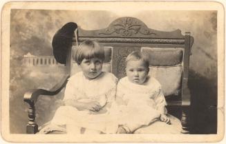 Two children seated on carved bench